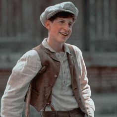 a young boy wearing a hat and vest