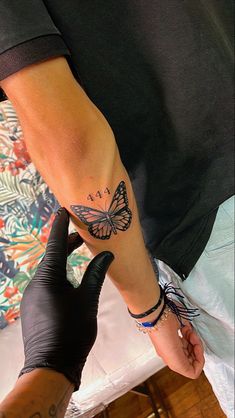 a person with a butterfly tattoo on their arm and another hand holding something in front of them