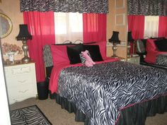 a bedroom with zebra print bedding and red curtains