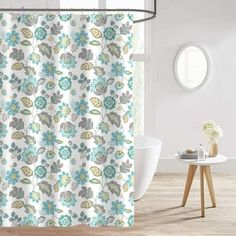 a shower curtain with blue and green flowers on it in front of a white bath tub