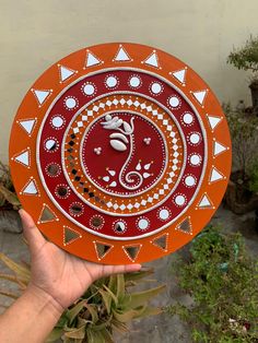 a hand holding an orange and white decorative plate