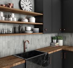 a black kitchen sink sitting under a clock on a wall next to some shelves with cups and mugs