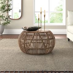 a wicker table with candles on it in front of a large mirror and couch