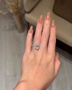 a woman's hand with a diamond ring on her left hand, in front of a couch