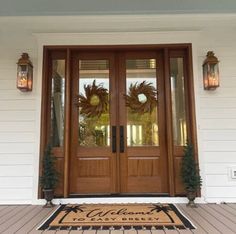 the front door is decorated with wreaths and two lights on either side of it