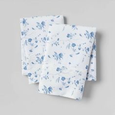 two white and blue floral napkins on top of each other with one folded in half