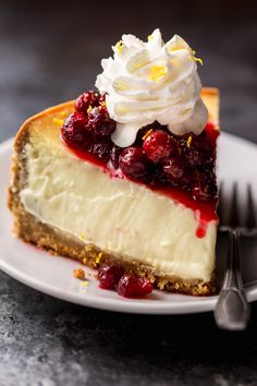 a piece of cheesecake with whipped cream and cherries on top sits on a plate