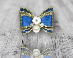 two bows with pearls on them sitting on a wooden surface