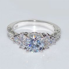 a white gold engagement ring with three stones on the side and an intricate band around it