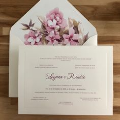 the wedding card is in front of an envelope with pink flowers and leaves on it