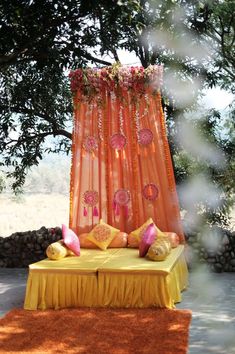 a bed sitting under a tree next to a lush green field