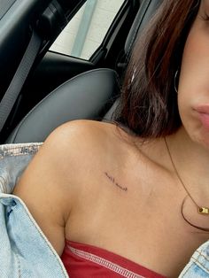 a woman with a small tattoo on her chest in the back seat of a car