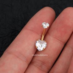 a pair of heart shaped diamond earrings on someone's finger