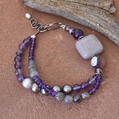 Varying shades of purple, violet, lavender, and gray come together in this beautiful multi strand bracelet. It features natural amethyst, Botswana agate, jasper, freshwater pearls, gray labradorite, and czech glass.   This bracelet has a sterling silver lobster clasp and measures 7 inches with a 1 inch extender chain.  Comes in a gift box, perfect for giving. Purple Double Strand Jewelry With Natural Stones, Purple Double Strand Natural Stones Jewelry, Double Strand Purple Jewelry With Natural Stones, Bohemian Lavender Beaded Bracelets, Elegant Gray Bracelets With Natural Stones, Bohemian Amethyst Lavender Bracelet, Handmade Purple Multi-strand Bracelets, Handmade Purple Multi-strand Bracelet, Adjustable Purple Double Strand Jewelry