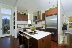 a modern kitchen with wood floors and stainless steel appliances in the middle of the room