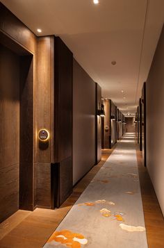 an empty hallway leading to two elevators in a hotel or office building with wood paneling on the walls