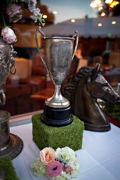 three trophies sitting on top of a table next to each other with flowers in front of them