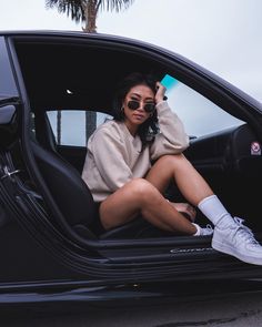 a woman sitting in the drivers seat of a car with her feet on the door