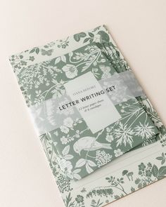 a green and white flowered paper with the words letter writing set on it