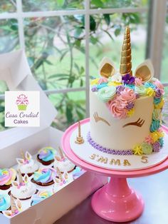 there is a unicorn cake and cupcakes on the table next to each other