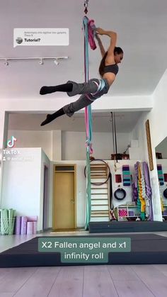 a woman doing aerial acrobatics on a pole in the middle of a room