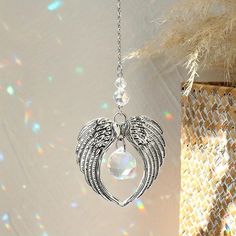 an angel wing and crystal bead necklace hangs from a chain on a white background