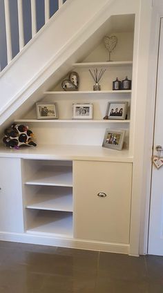 a white book shelf under a stair case