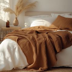 an unmade bed with brown blankets and pillows