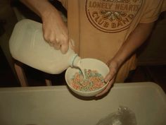 a man is pouring milk into a bowl filled with cereal and sprinkles