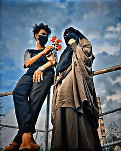 two women in burkas are standing next to each other and one is holding a flower