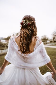 a woman in a white dress is sitting on the grass with her back to the camera