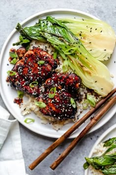 two plates with rice, meat and vegetables next to chopsticks on a table