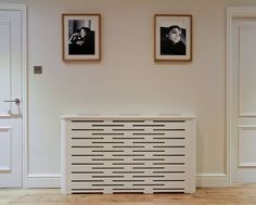 a white radiator sitting on top of a hard wood floor next to two framed pictures