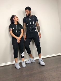 a man and woman standing next to each other in matching black outfits with air jordan sneakers