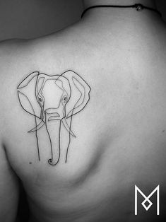 an elephant tattoo on the back of a woman's shoulder