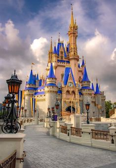 a castle with blue turrets and lights on it's sides in front of a cloudy sky