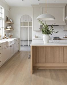 a large kitchen with white cabinets and wood flooring on the countertops, along with an island