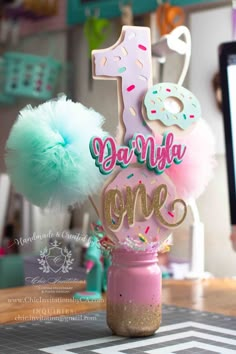 a pink and blue cake topper with the number one on it sitting in a mason jar