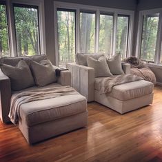 a living room filled with lots of windows and furniture next to each other on top of a hard wood floor