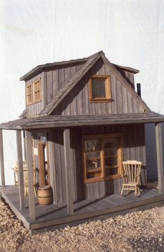 a doll house made out of wood sitting on top of gravel