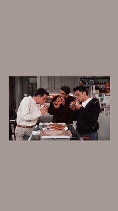 four men standing around a table eating food