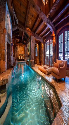 a large indoor swimming pool in the middle of a living room with stone fireplaces