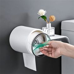 a person opening a toilet paper dispenser on a wall with a flower in it