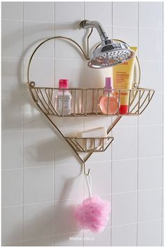 a heart shaped shower shelf with soap, shampoo and lotion on it next to a white tiled wall