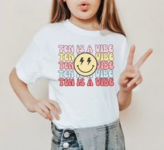 Celebrate her 10th birthday with this groovy TEN is a vibe birthday shirt. ..♥..Unisex fit Jersey Short-Sleeve T-Shirt..♥.. Available sizes: YOUTH: S(6/8) M(10/12) L(14/16) XL (18) ADULT: S M D E T A I L S Pre-shrunk fabric Solid Colors: 100% combed and ring-spun cotton Heather Colors: 52% ring-spun cotton, 48% polyester Athletic and Black Heather: 90% ring-spun cotton, 10% polyester This is a direct to garment print, no vinyl or stencils. PRODUCTION & SHIPPING - Please allow 2-10 business days for your order to be processed and made - Standard shipping takes 3-5 days - Please note that these times are estimated by USPS and may take longer - Please make sure your shipping address is correct before placing an order - Printed and Shipped in the USA Machine wash cold, inside-out, gentle cycle Ten Is A Vibe Birthday, 10th Birthday Girl, 10th Birthday Shirt, Eleventh Birthday, Girls Birthday Shirt, Tie Dye Birthday, Tenth Birthday, Girl Bday Party, Birthday Words