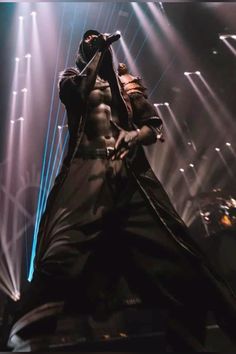 a man standing on top of a stage with his hands in the air and lights behind him