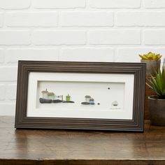 three small boats in a shadow frame on a table next to a succulent plant