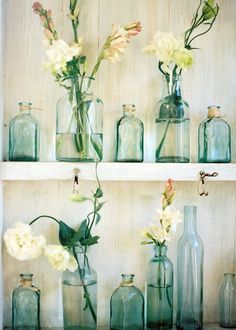 several glass bottles with flowers in them on a shelf