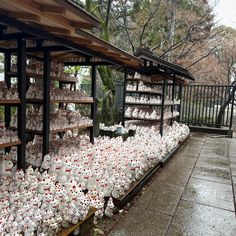 rows of white vases are lined up on the shelves in front of a building