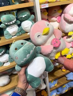 a person holding a stuffed animal in front of shelves with other stuffed animals on it